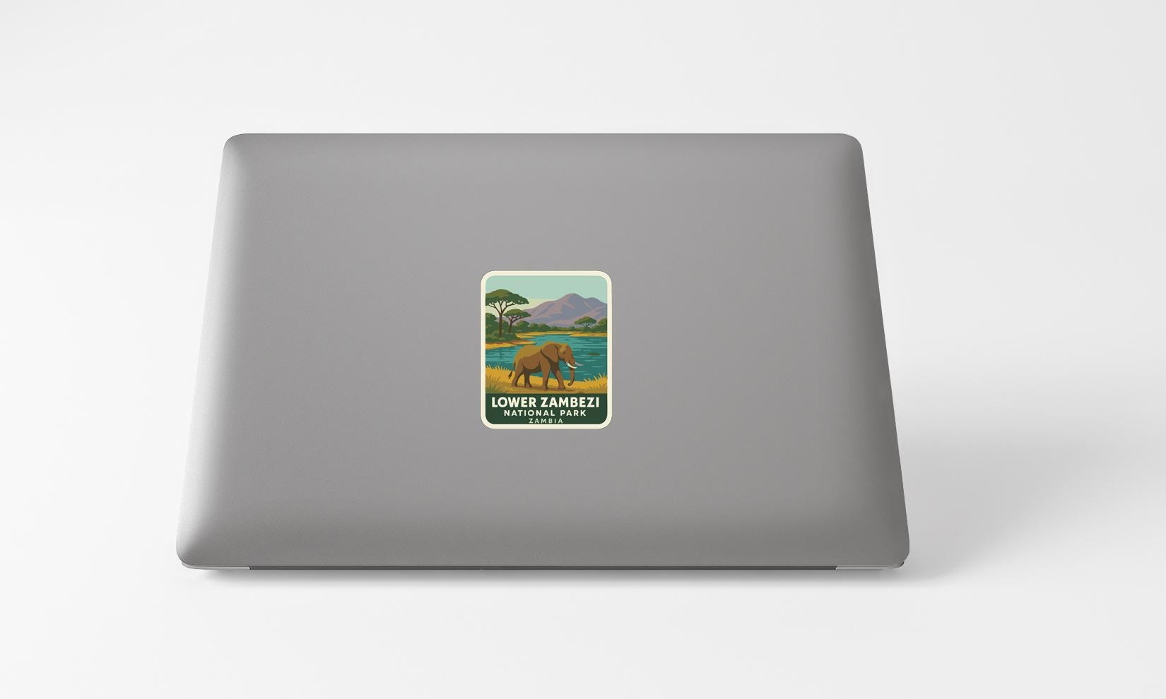 A sticker on the back of a laptop, depicting a scenic landscape with a river and mountains.