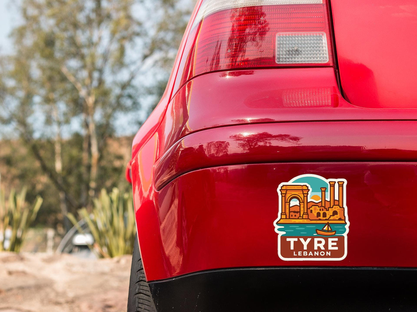 the rear end of a red car with a sticker on it, featuring an illustration of a cityscape and the word "TYRE" written on it.