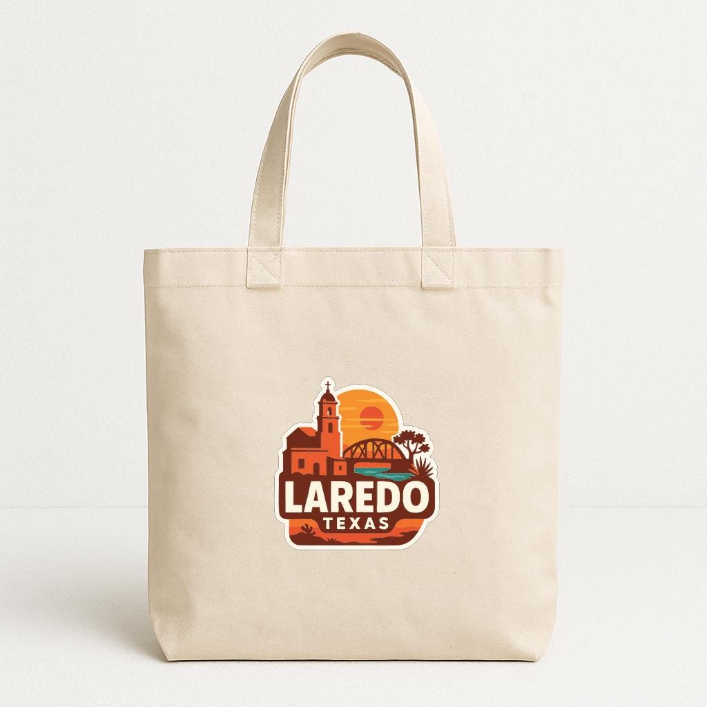 A beige tote bag with a printed design featuring a sunset, a building, and the text "LAREDO TEXAS".