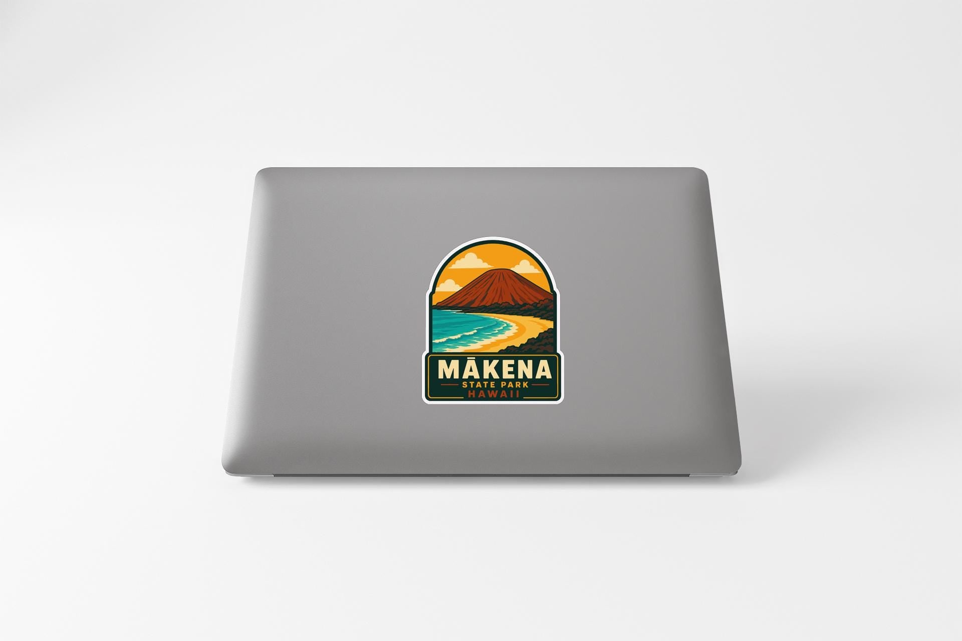 A sticker on the back of a laptop, depicting a scenic landscape with a mountain and a beach.