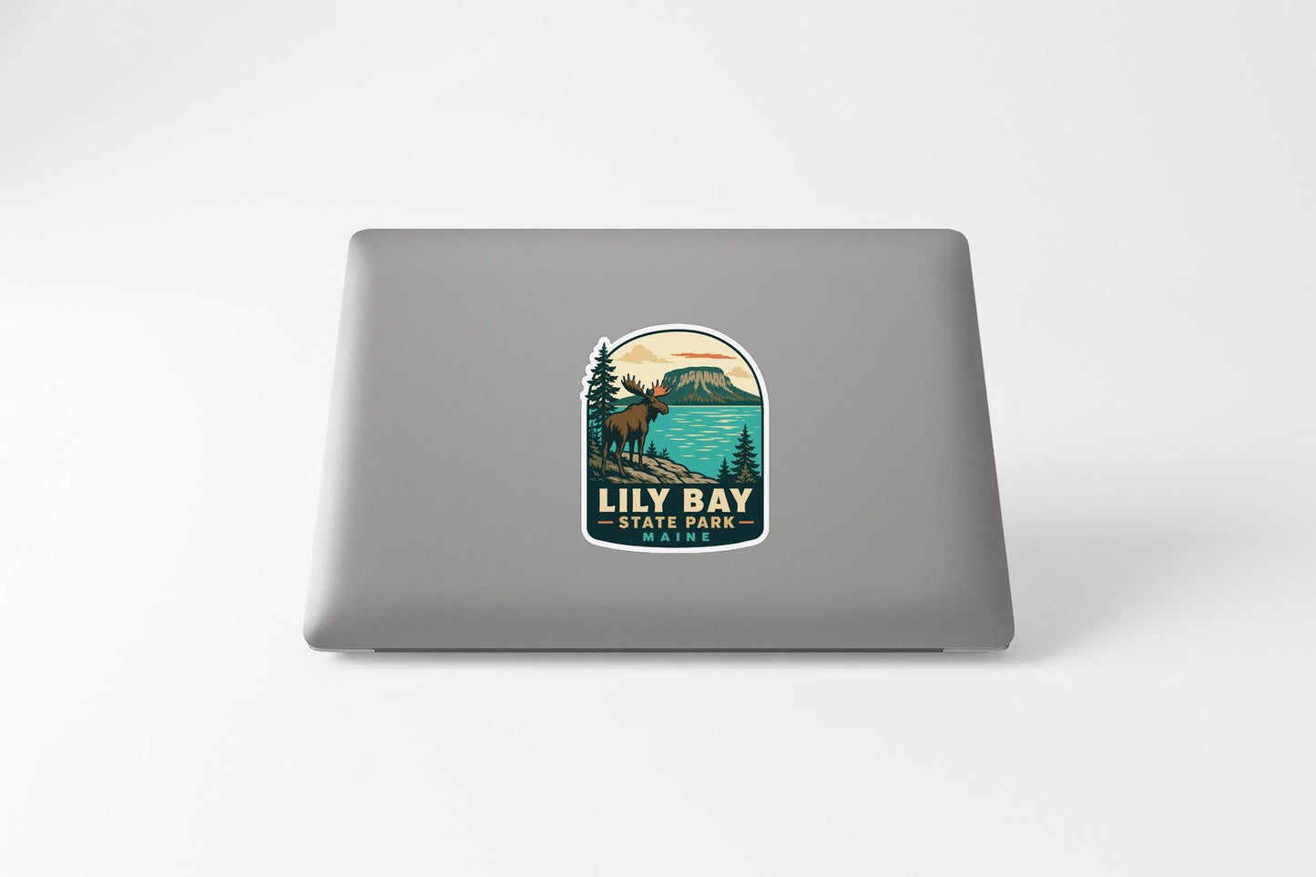 A sticker on the back of a laptop, depicting a scenic landscape with a moose, trees, and a lake.