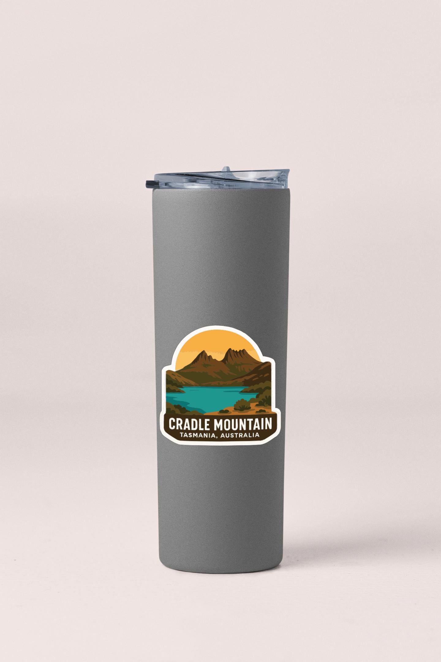 A gray insulated tumbler with a sticker depicting a scenic mountain landscape.