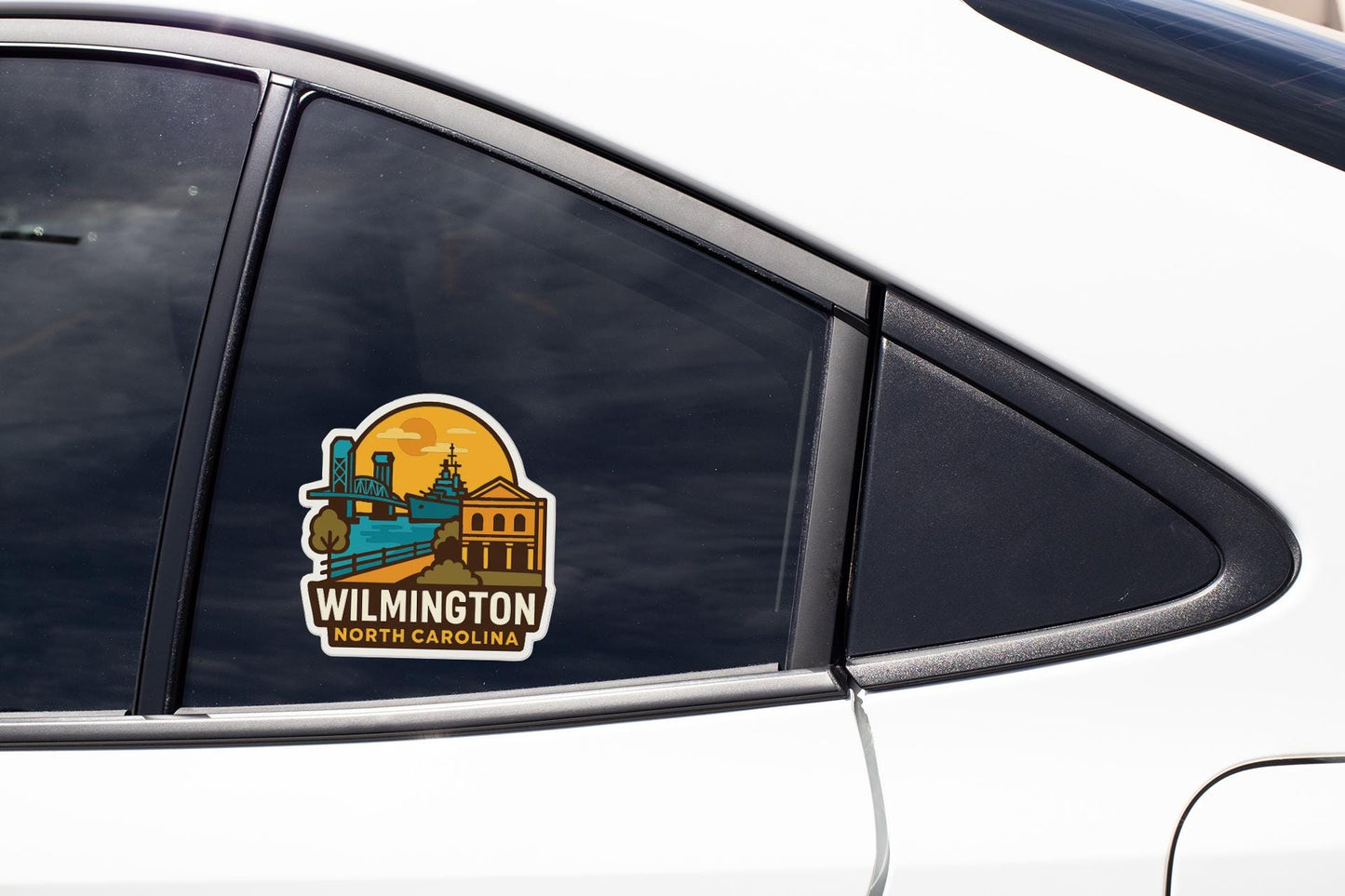 A sticker on the side of a car window, depicting a cityscape with a train and buildings, along with the text "WILMINGTON NORTH CAROLINA".