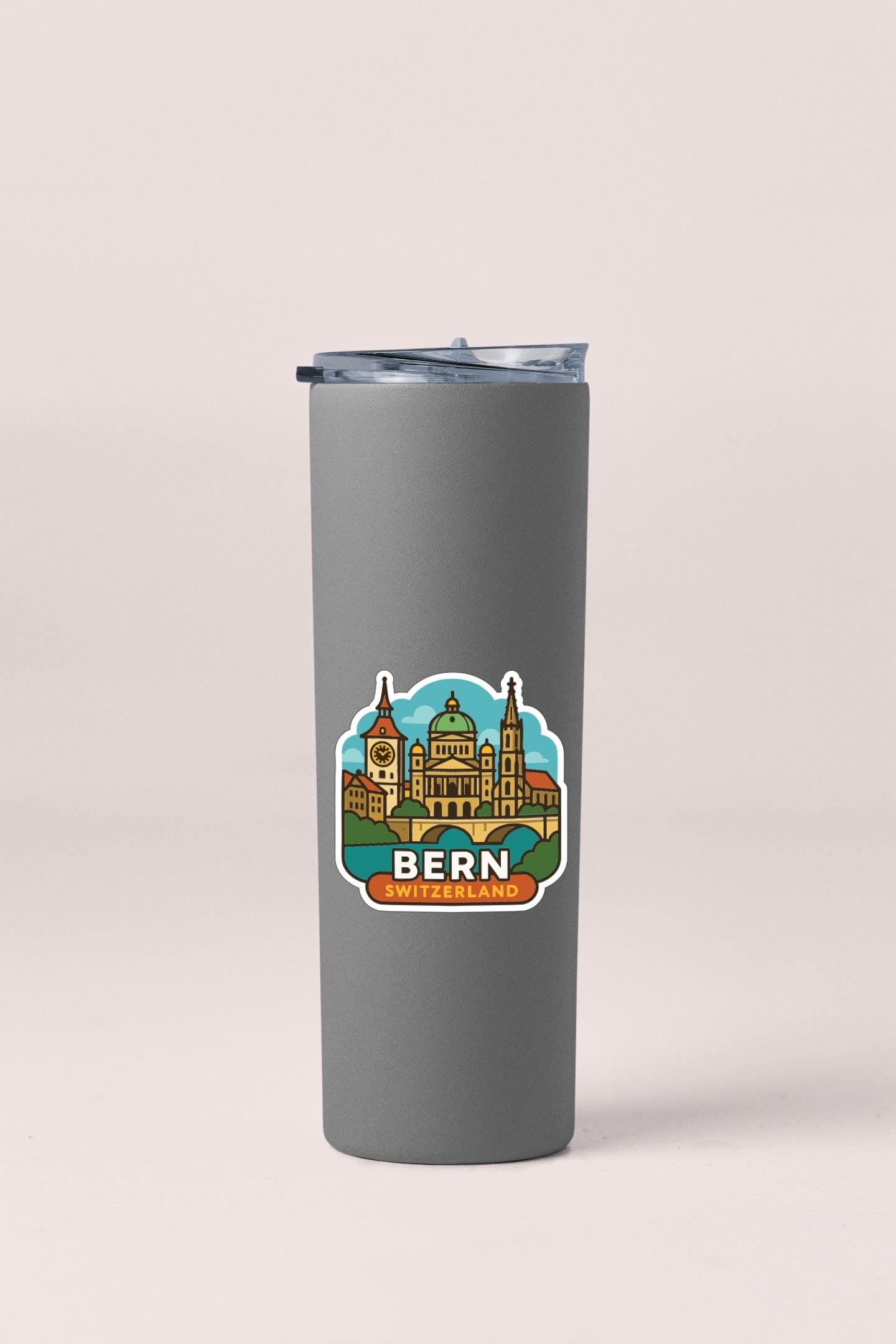 A gray insulated tumbler with a sticker depicting the Bern, Switzerland skyline.