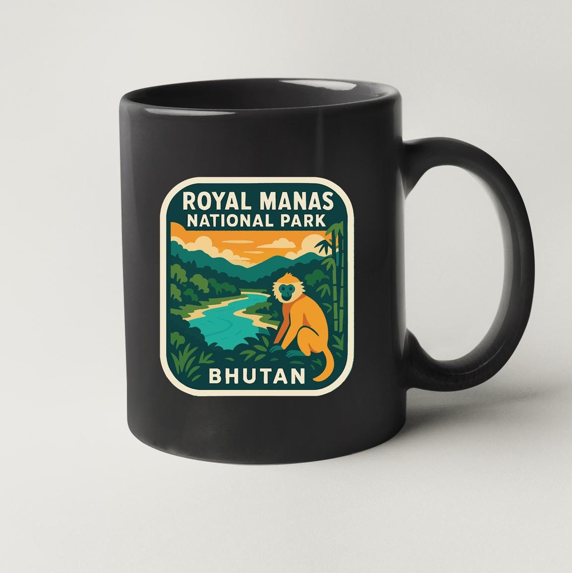 A black coffee mug with a graphic design depicting a monkey in a jungle setting, along with text that reads "ROYAL MANAS NATIONAL PARK BHUTAN".
