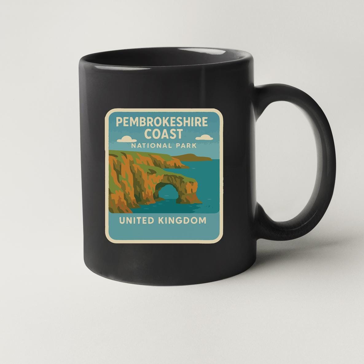 A black coffee mug with a label that says "Pembrokeshire Coast National Park United Kingdom".