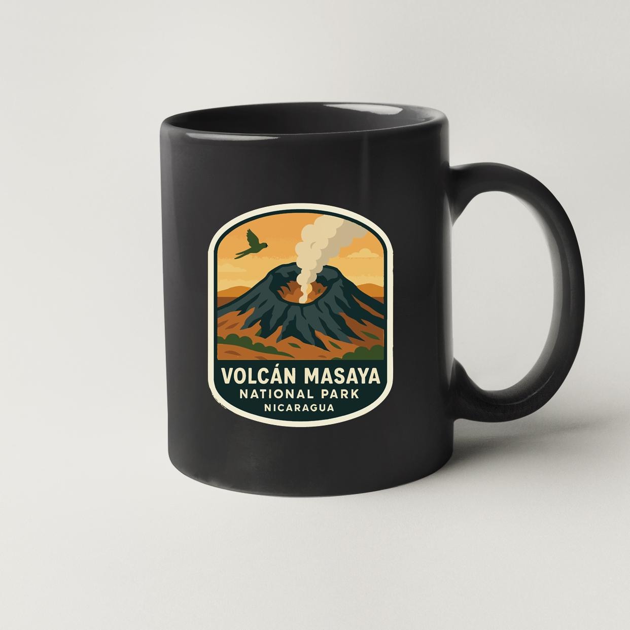 A black coffee mug with a graphic design depicting a volcano and a bird in flight, along with the text "Volcan Masaya National Park Nicaragua".