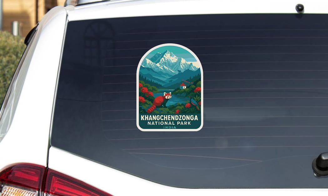 A sticker on the rear window of a car, depicting a scenic landscape with mountains, trees, and a red panda.