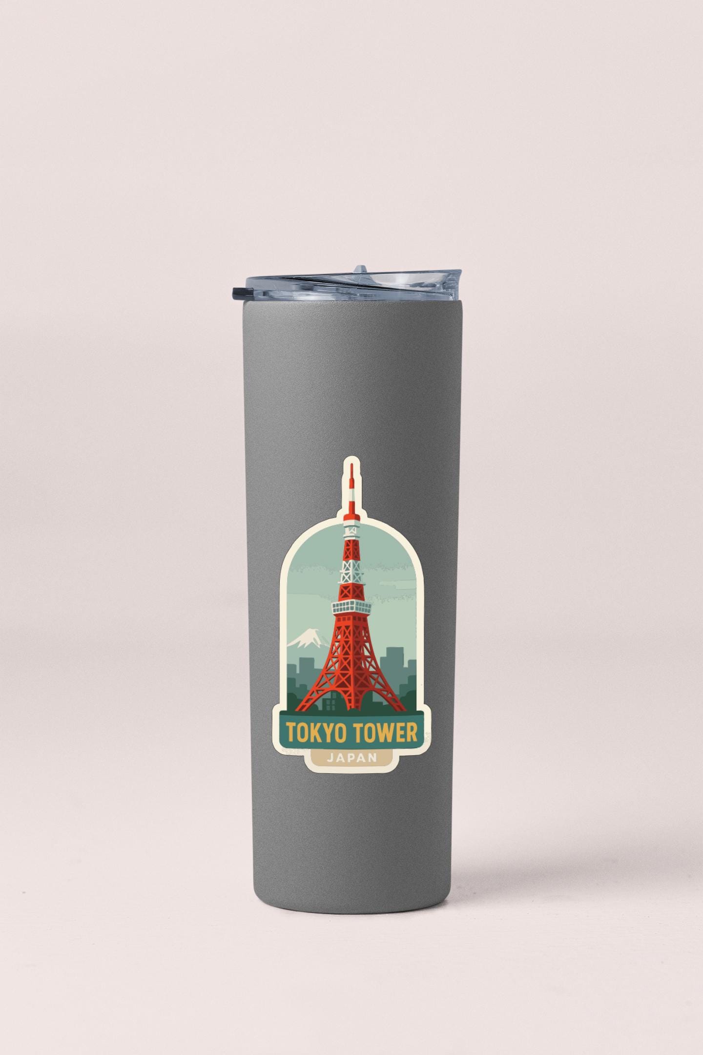 A gray insulated tumbler with a sticker depicting the Tokyo Tower in Japan.