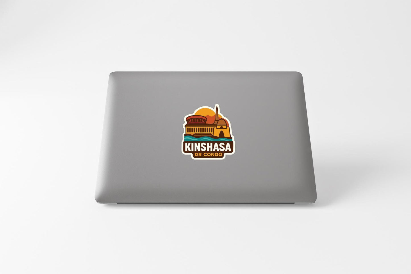 A sticker on the back of a laptop displaying a colorful illustration of a building with a sun in the background.