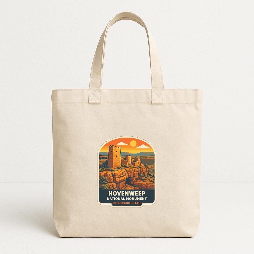 A beige tote bag with a printed label that says "HOVENWEEP NATIONAL MONUMENT", depicting a desert landscape with a castle or monument in the background.