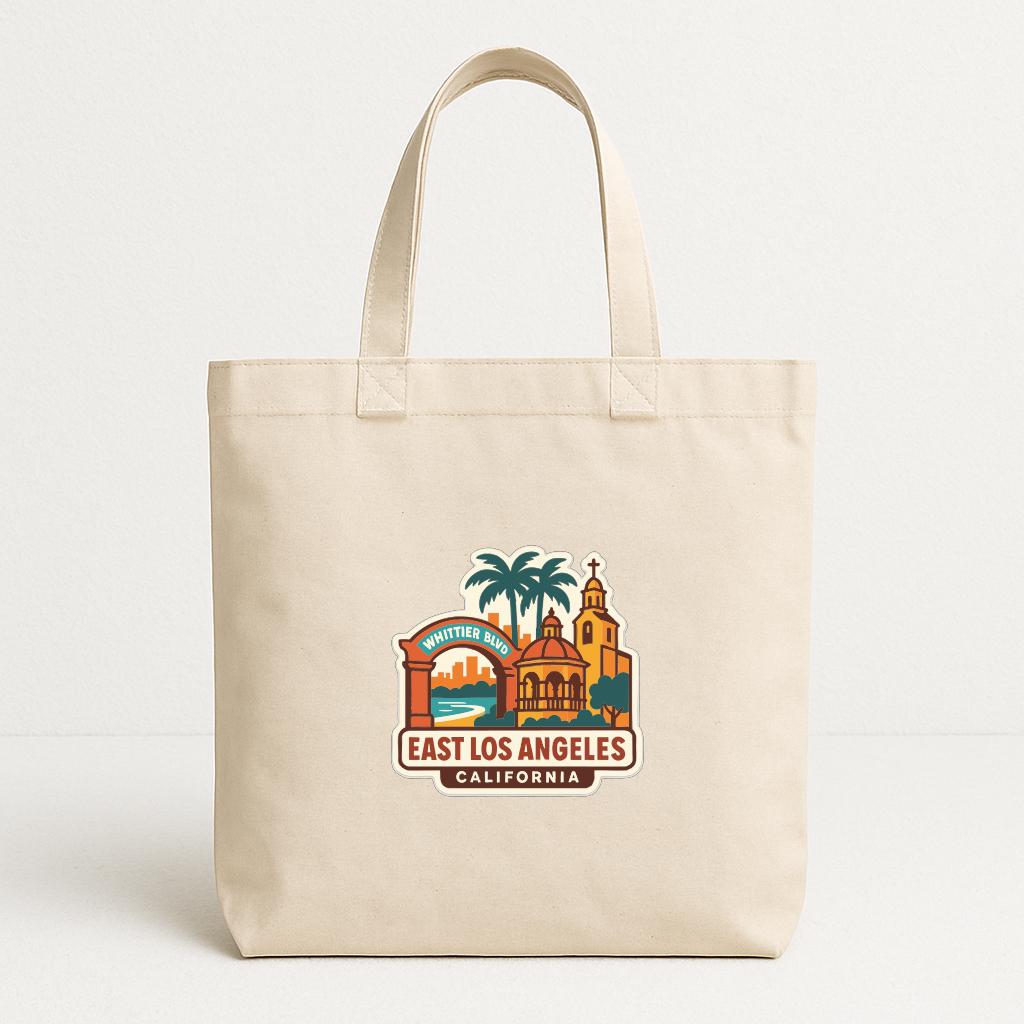 A beige tote bag with a printed design depicting landmarks and scenery from East Los Angeles, California.