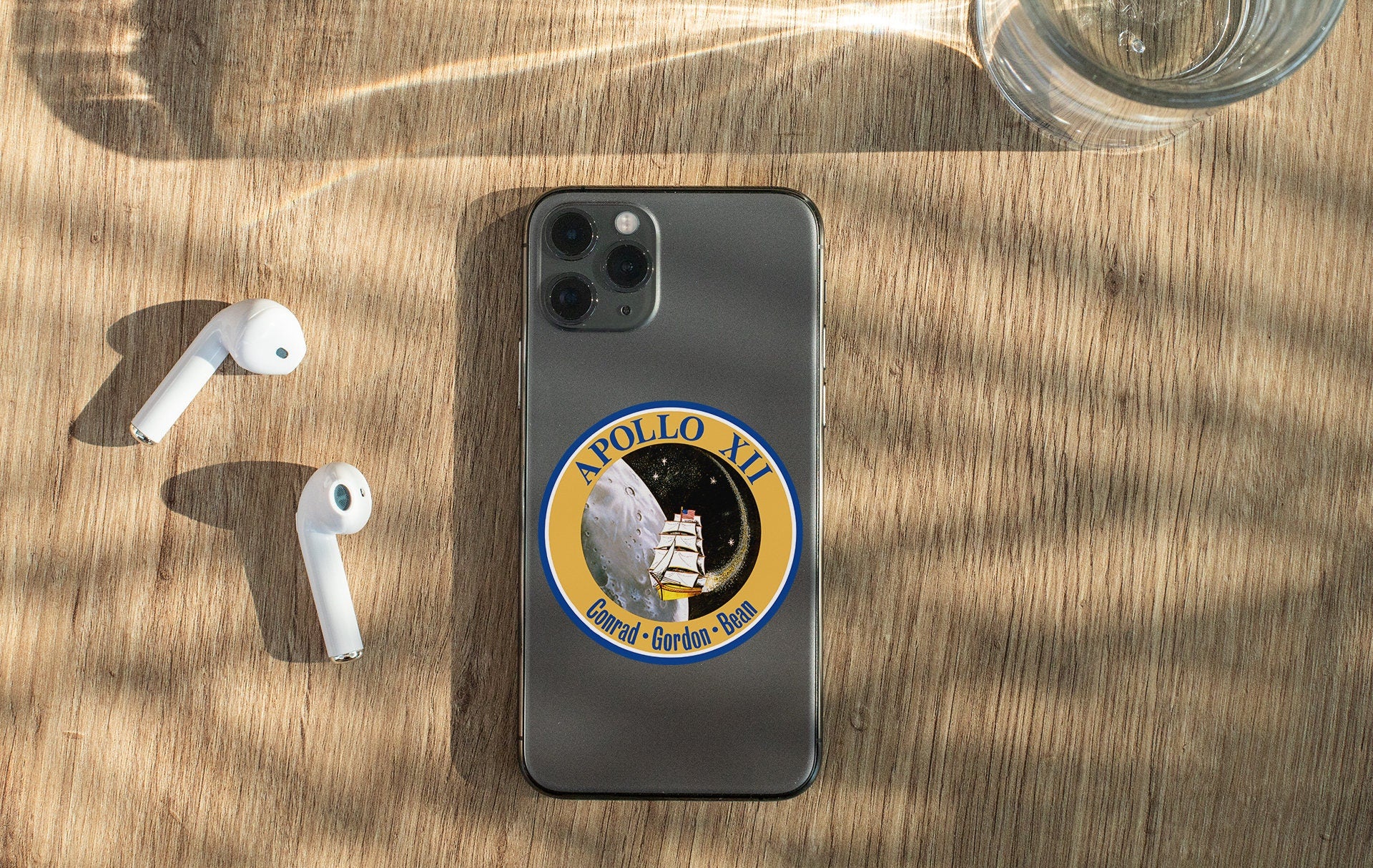 a cell phone with a sticker on it next to ear buds