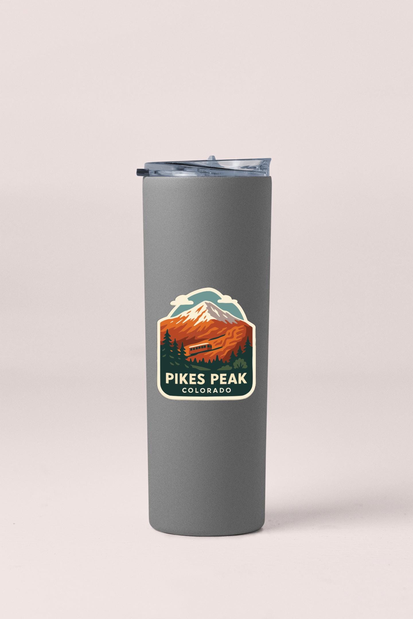 A gray insulated tumbler with a mountain landscape sticker on it.