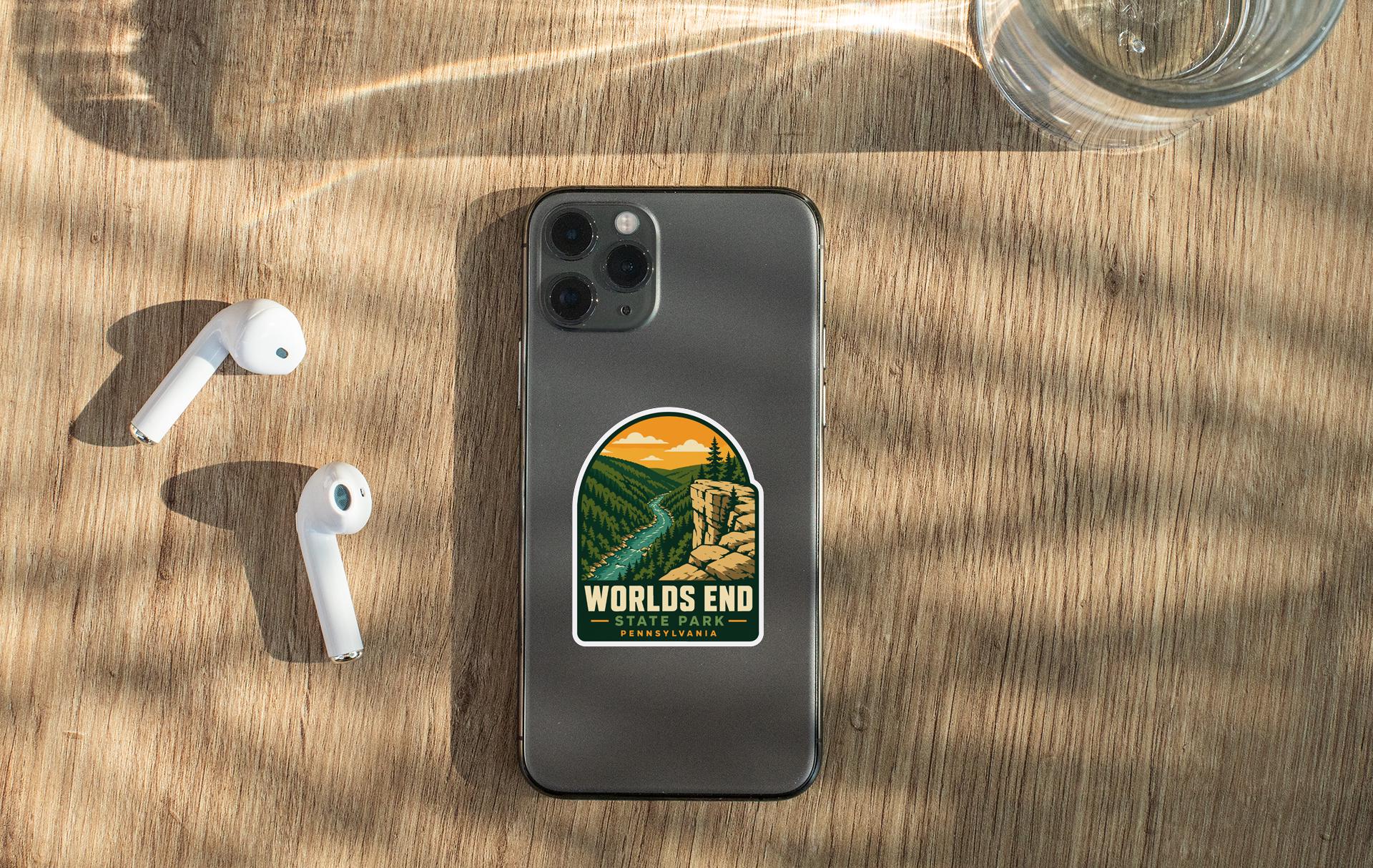 a smartphone with a sticker on the back, along with a pair of white earbuds and a glass of water on a wooden surface.