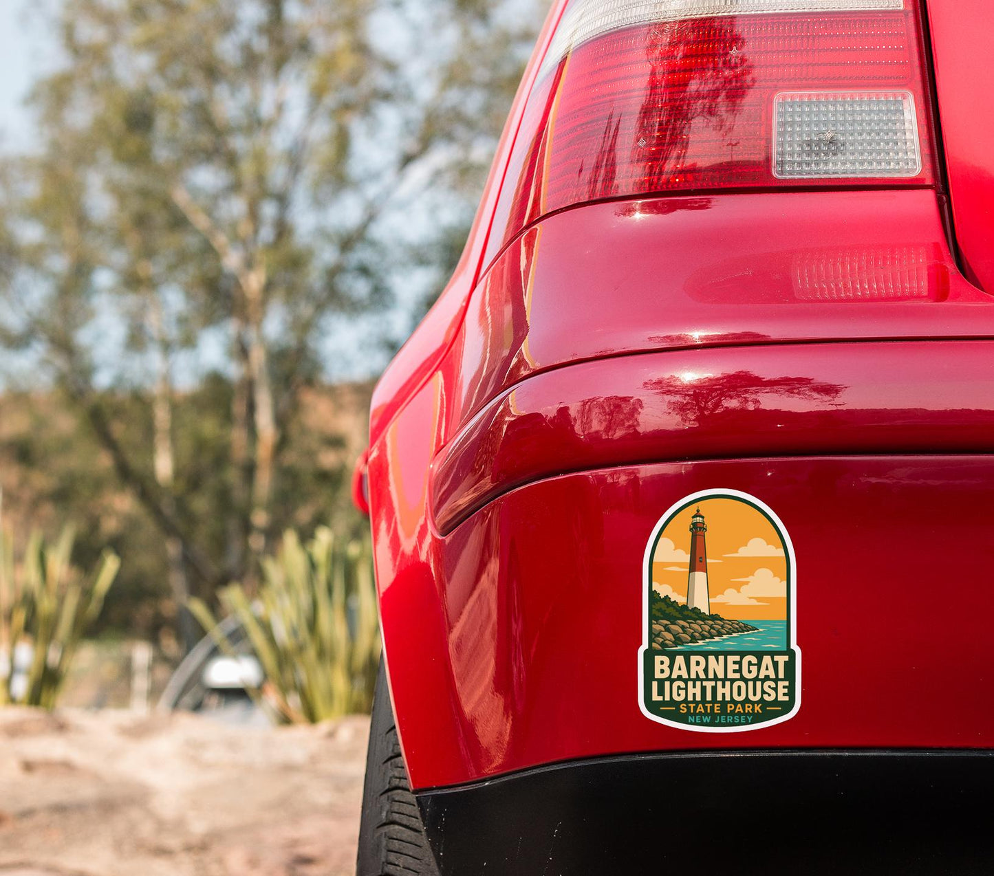 the rear end of a red car with a sticker on the trunk that says "Barnecat Lighthouse".
