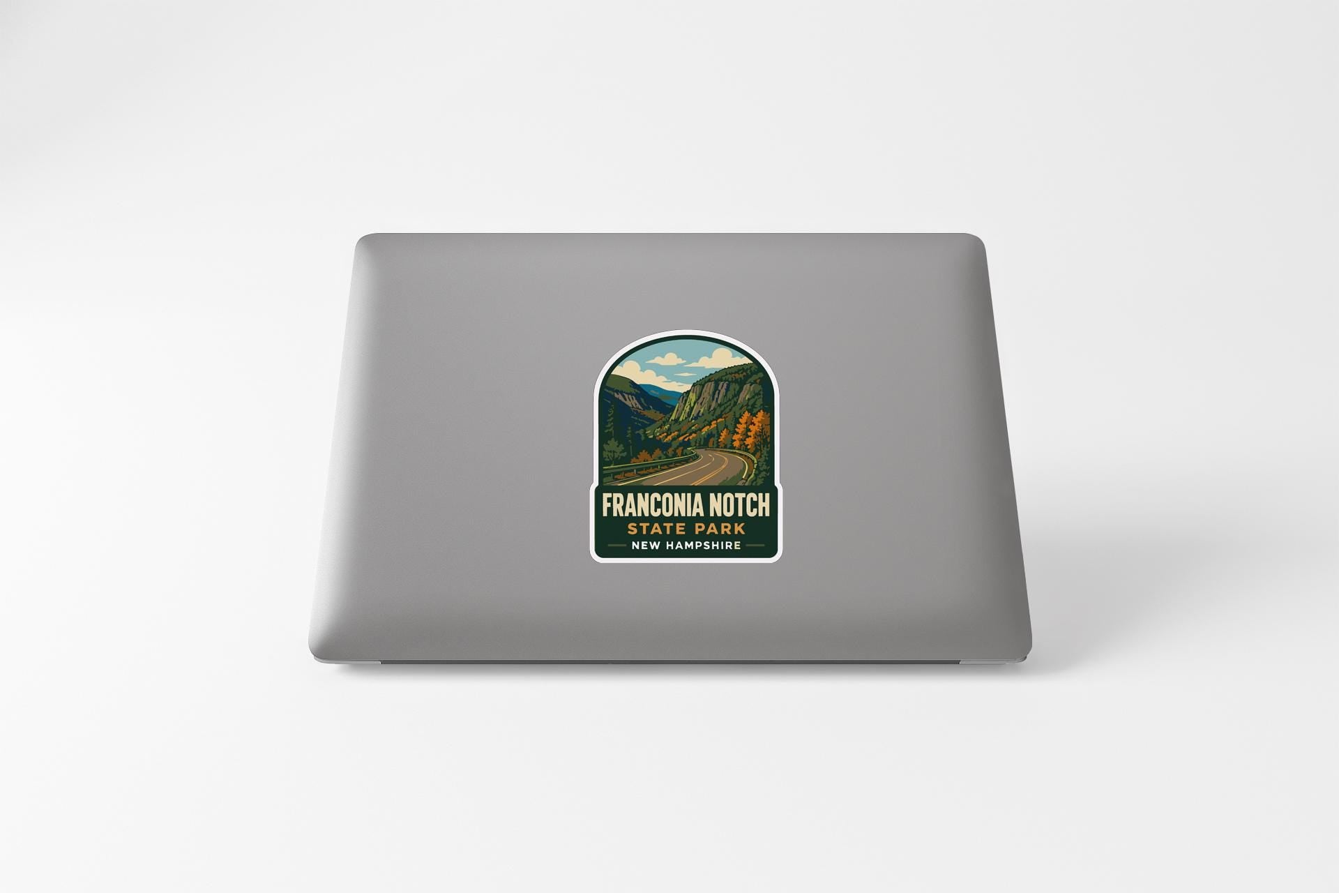 a sticker on a laptop with a scenic mountain landscape and a road.