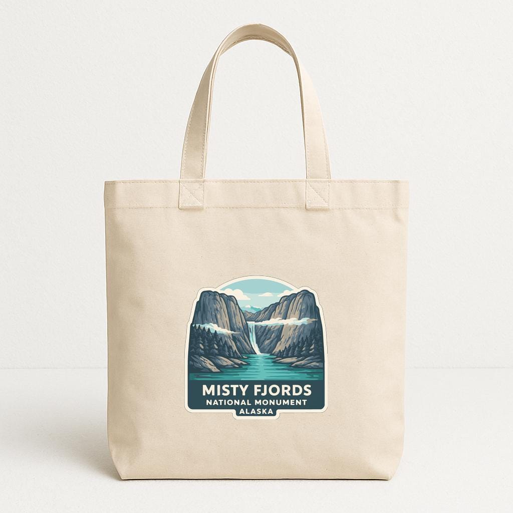 A beige tote bag with a printed design featuring the Misty Fjords National Monument in Alaska.