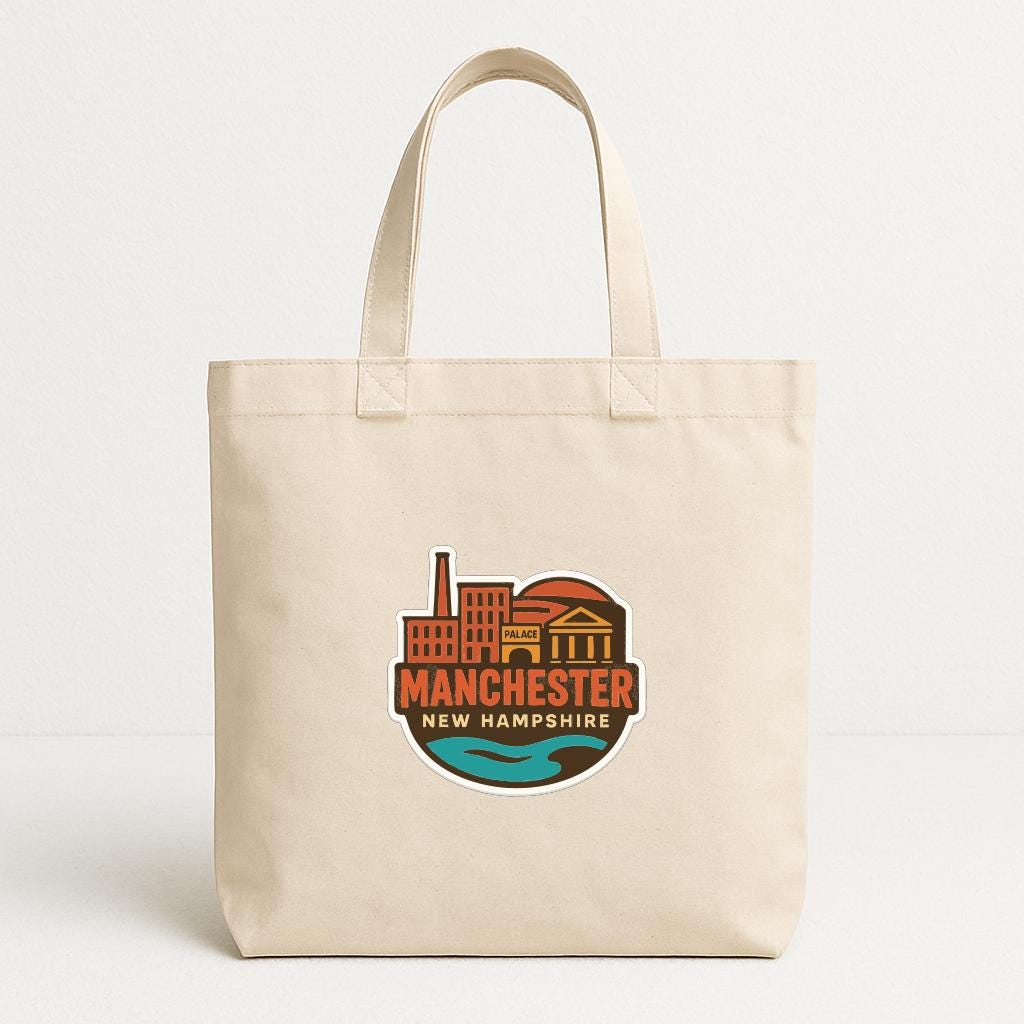 A beige tote bag with a graphic design featuring the text "MANCHESTER NEW HAMPSHIRE" and an illustration of a city skyline.