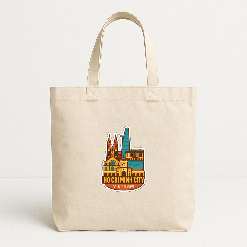 A beige tote bag with a colorful illustration of Ho Chi Minh City, Vietnam, printed on it.