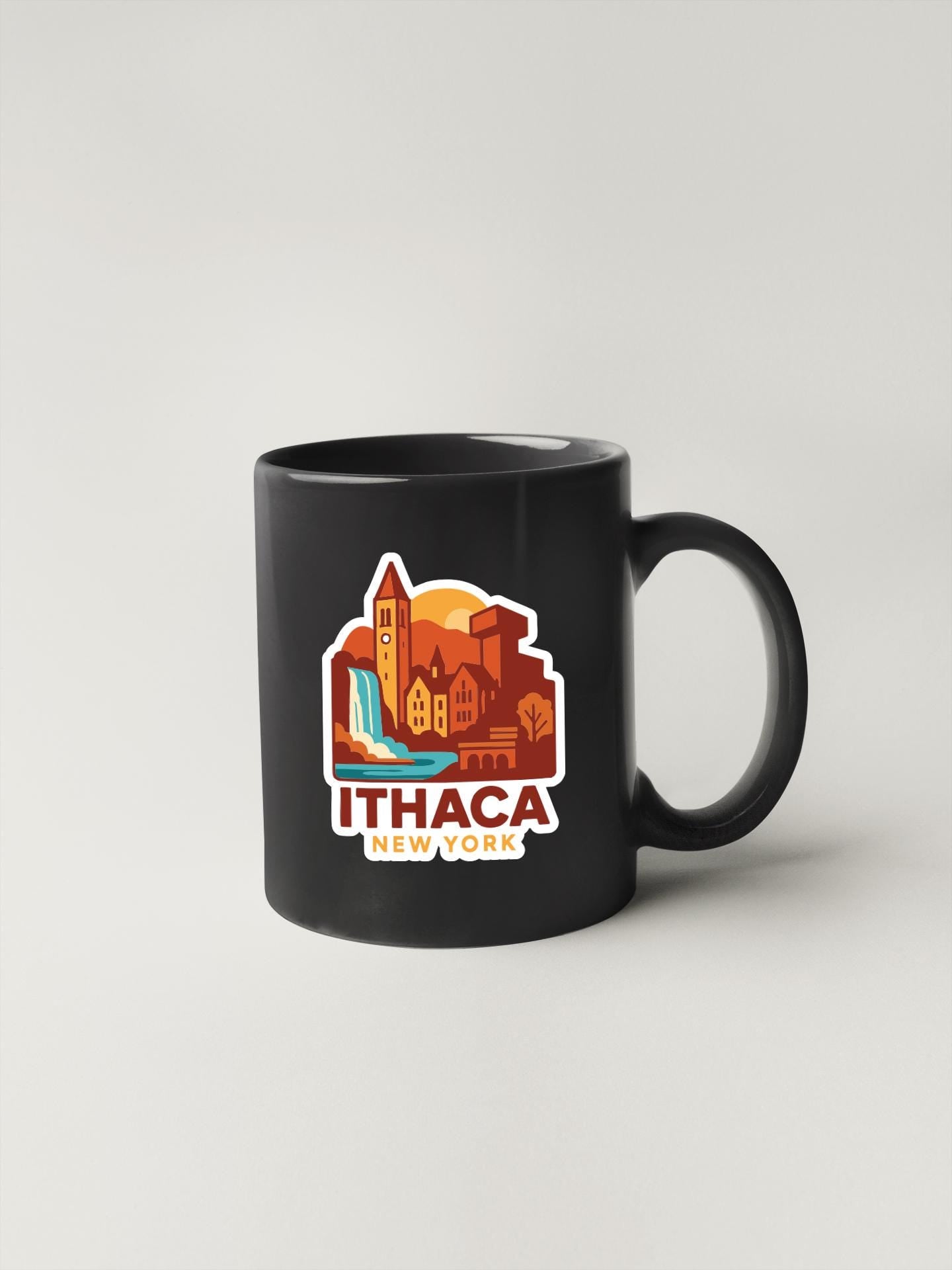 A black coffee mug with a colorful graphic depicting a cityscape and the text "Ithaca, New York" printed on it.