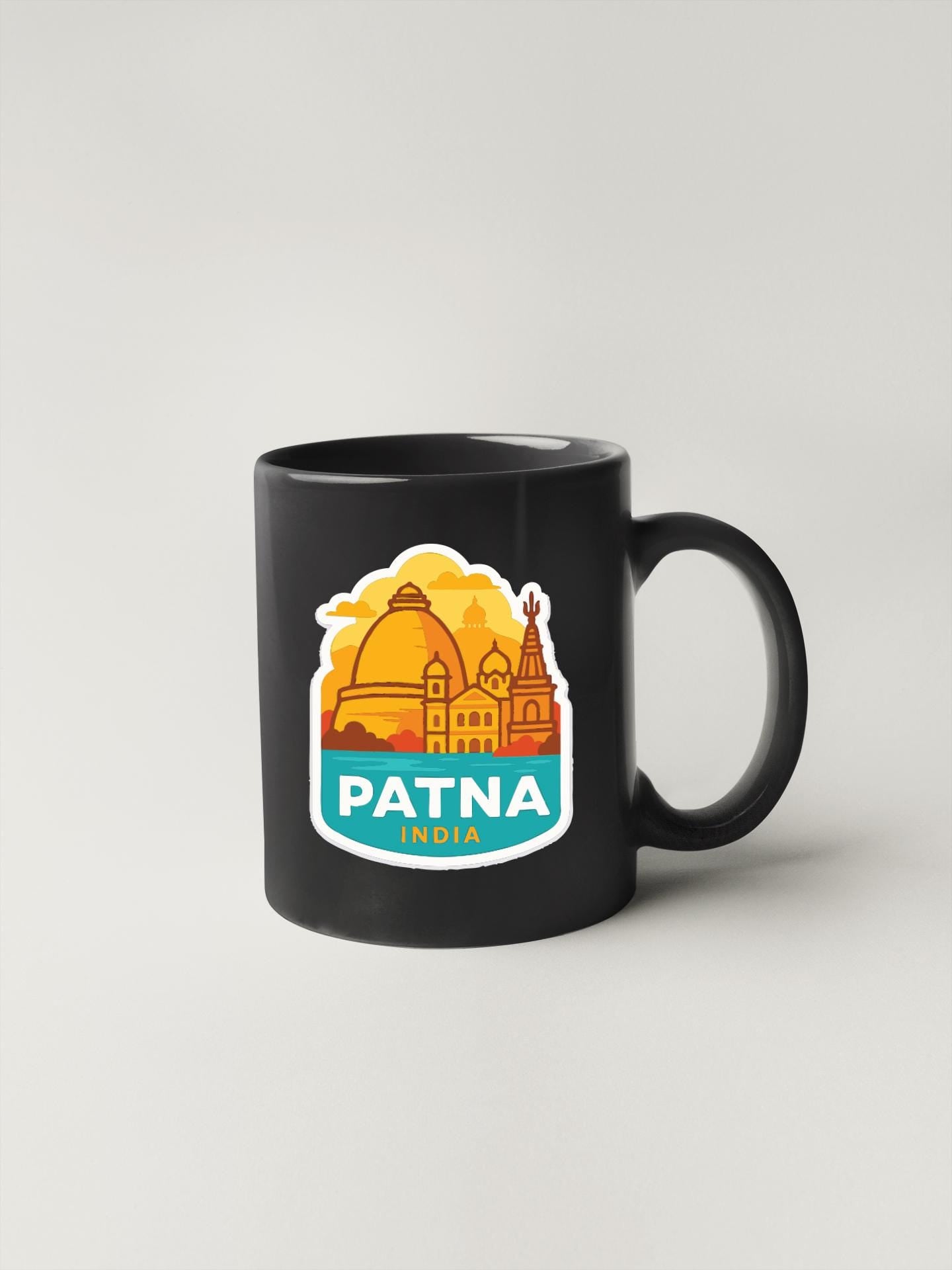A black coffee mug with a sticker depicting the city of Patna, India.