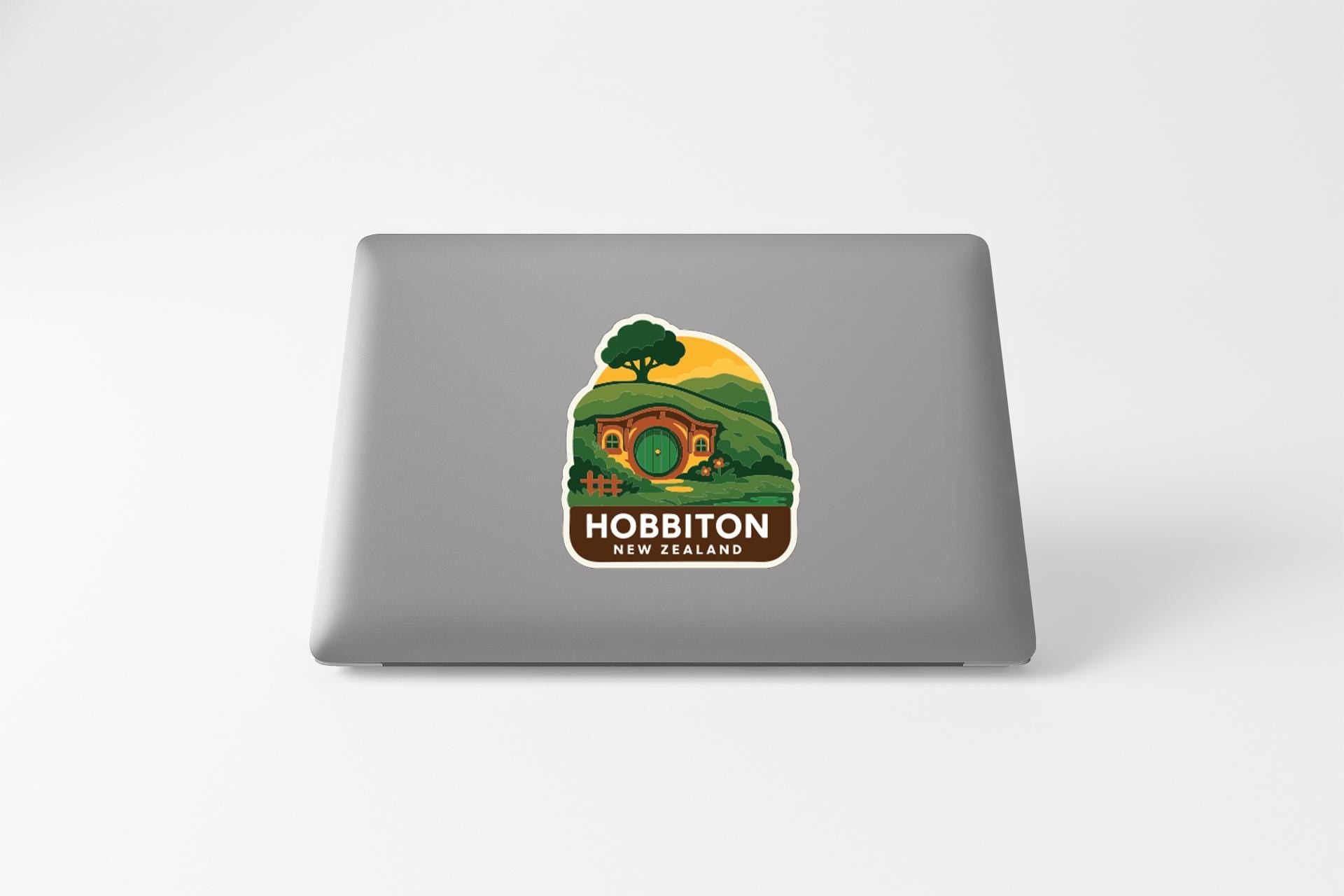A sticker featuring a landscape with a house and trees, along with the text "HOBLBITON NEW ZEALAND".