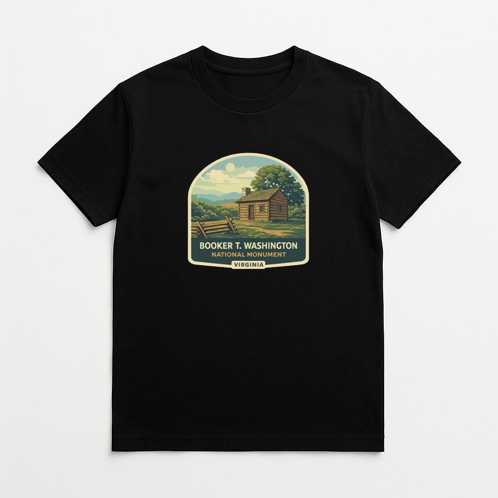 A black t-shirt with a graphic design depicting a cabin in a rural setting, surrounded by trees and a fence.