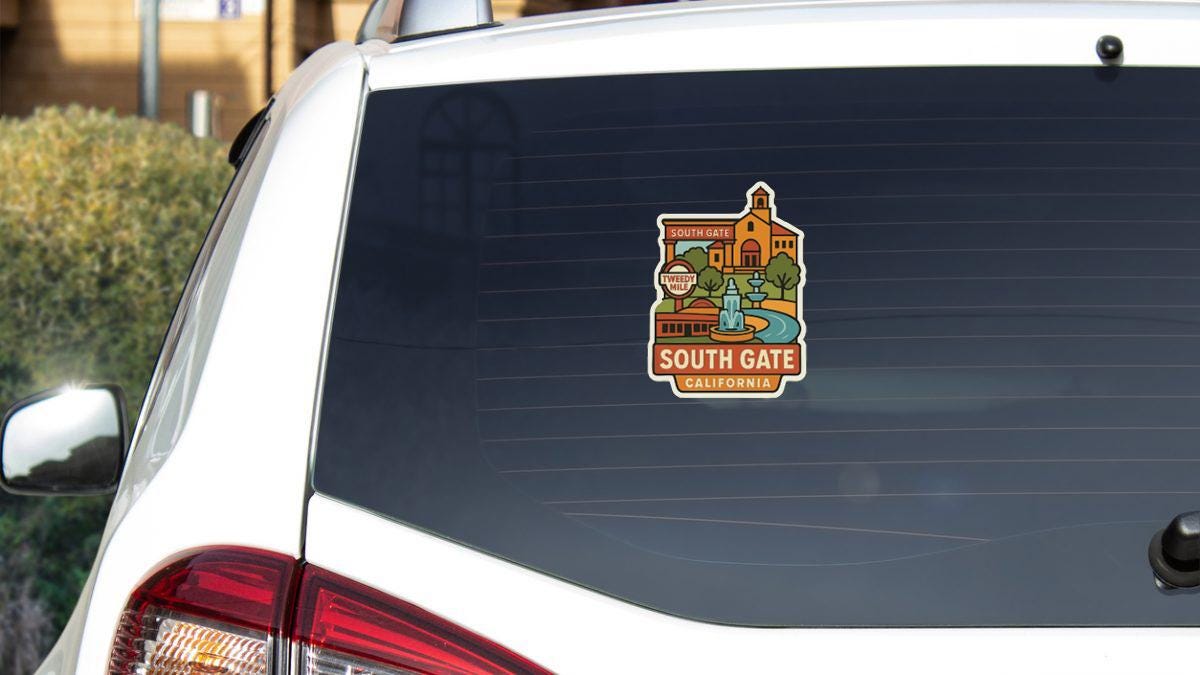A sticker on the rear window of a white car, depicting a scenic view of South Gate, California.