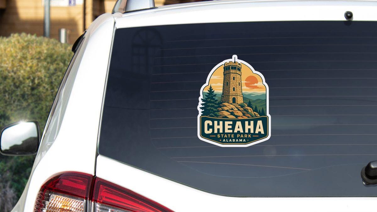 A sticker on the rear window of a white vehicle, depicting Cheaha State Park in Alabama.