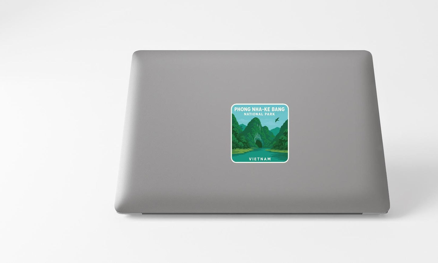 A sticker depicting a scenic landscape with mountains and a river, placed on the back of a laptop computer.