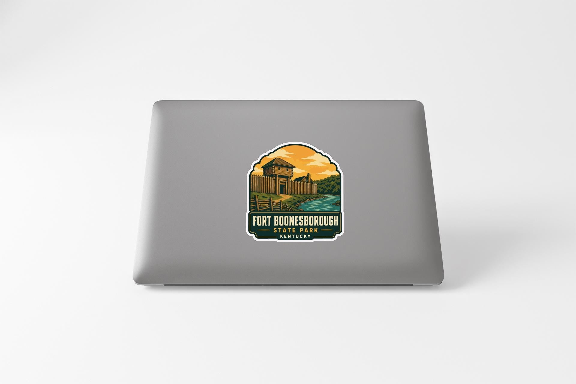a sticker on the back of a laptop, depicting a scenic landscape with a building and a river.
