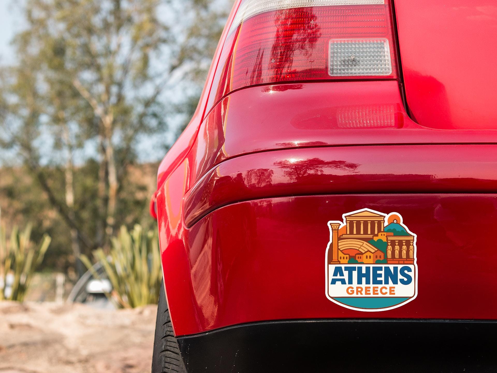 the rear end of a red car with a sticker on the trunk that says "Athens Greece".