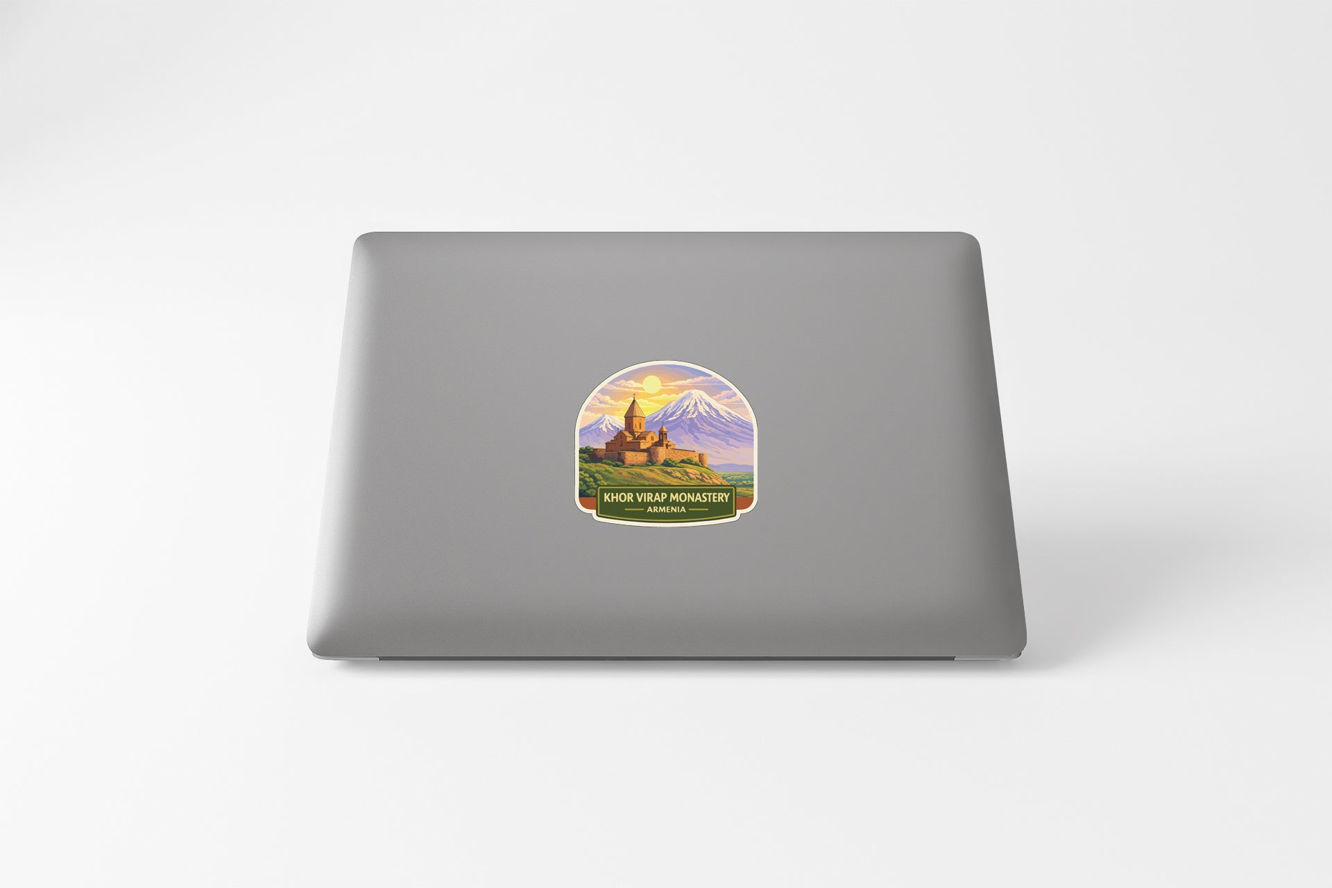 A sticker on the back of a laptop, depicting a castle and mountains.