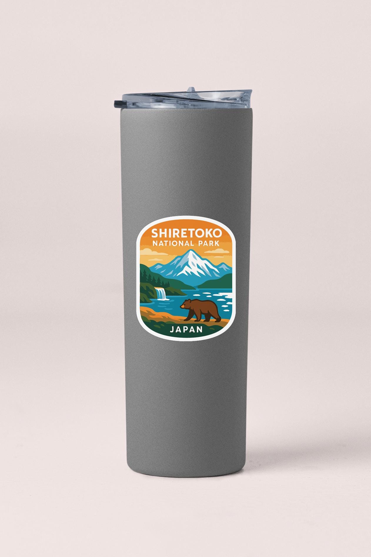A gray insulated tumbler with a sticker depicting a bear and mountains, representing Shiretoko National Park in Japan.