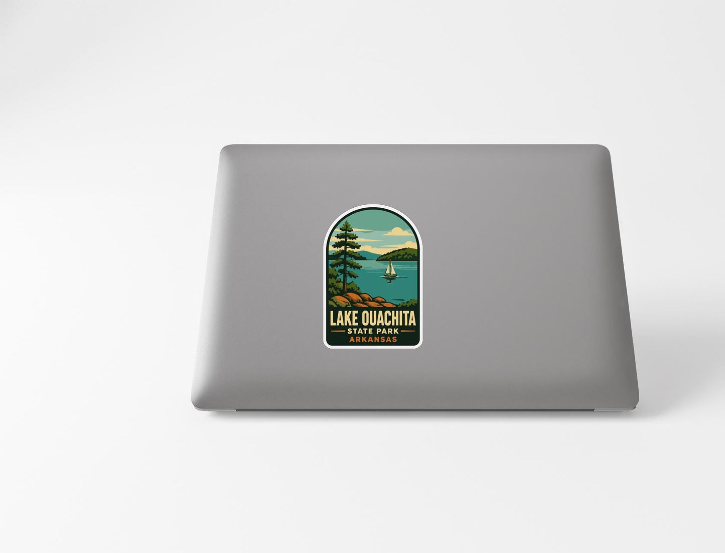 A sticker on the back of a laptop, depicting a scenic landscape with a lake, mountains, and a sailboat.
