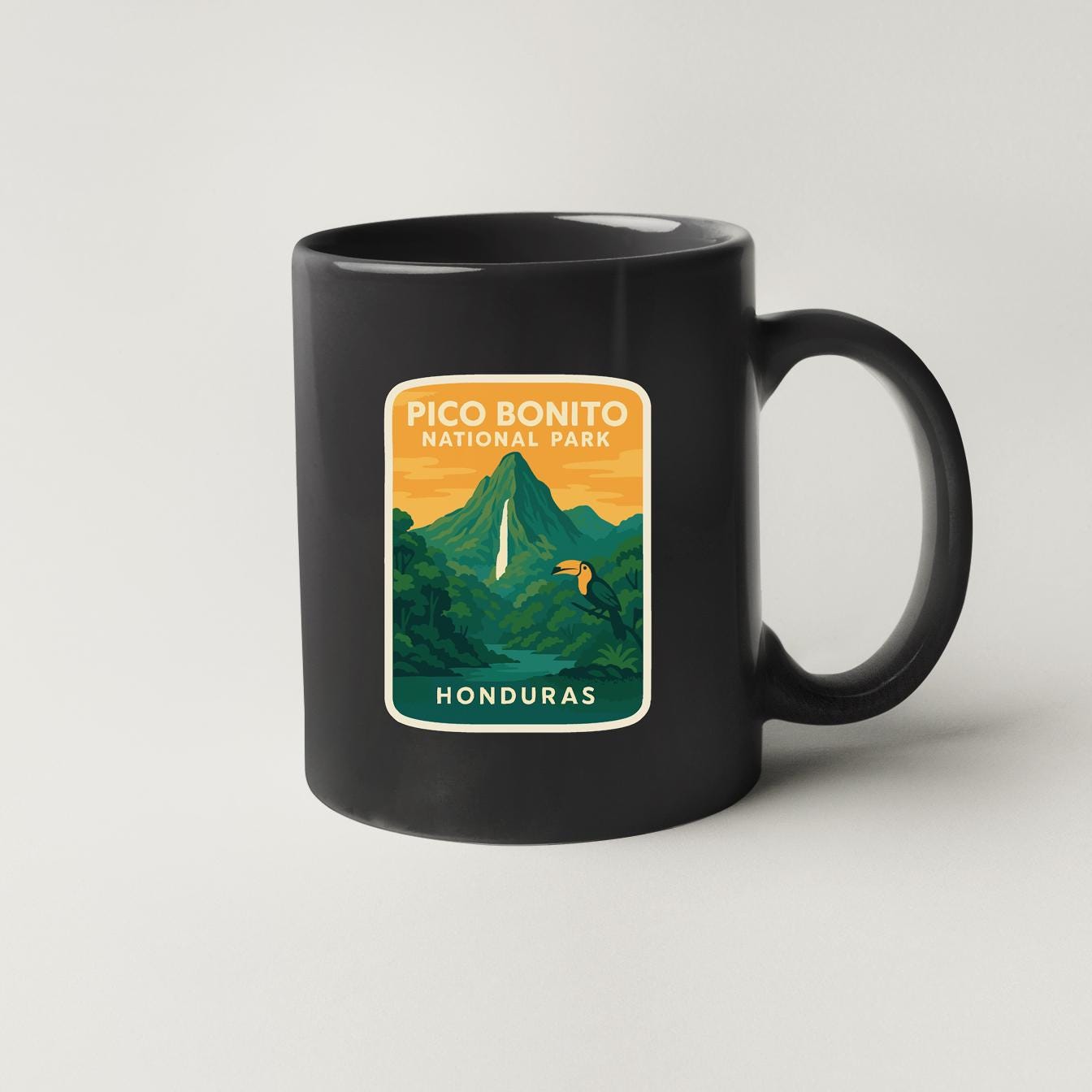A black coffee mug with a sticker depicting the Pico Bonito National Park in Honduras.