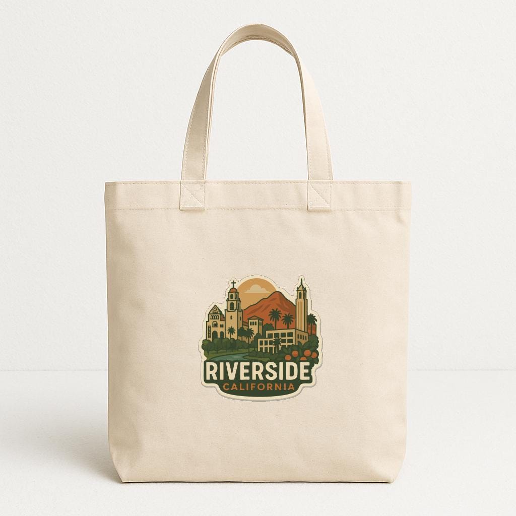 A beige tote bag with a printed design depicting a cityscape and the text "RIVERSIDE, CALIFORNIA" printed on it.