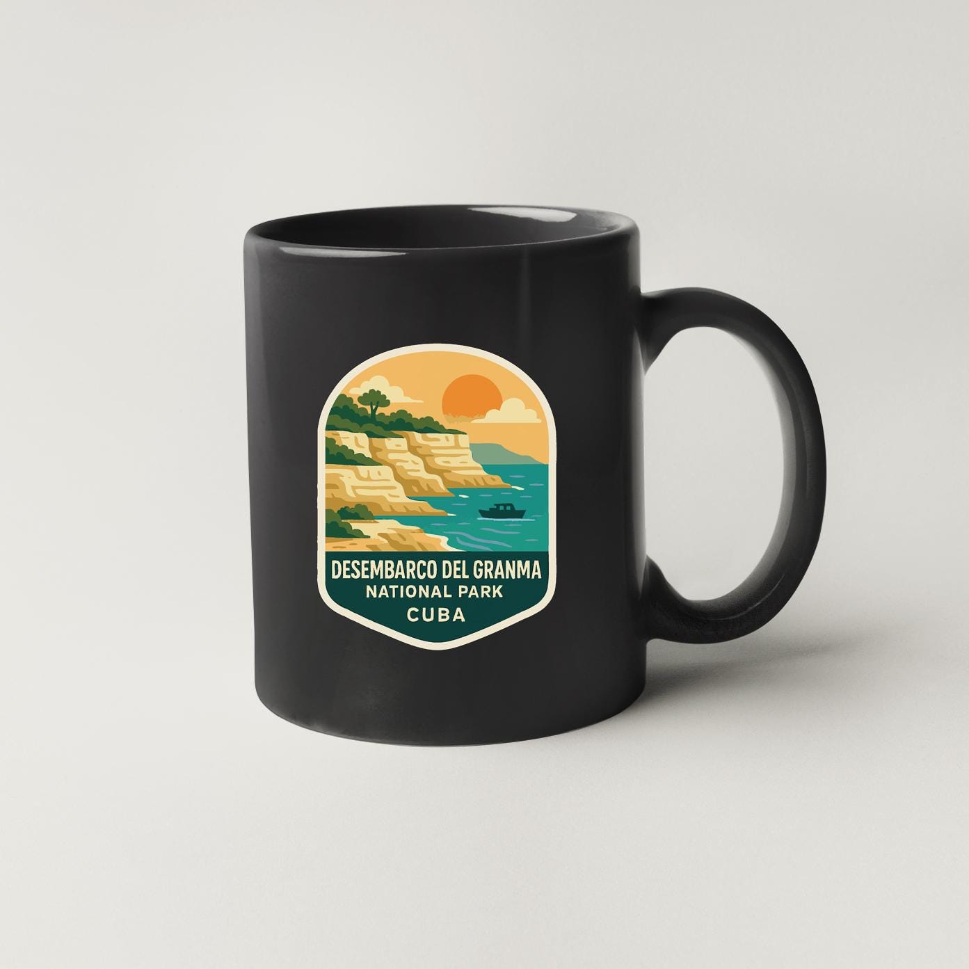 A black coffee mug with a colorful graphic depicting a scenic landscape, including cliffs, water, and a boat, along with the text "DESEMBRACCO DEL GRANMA NATIONAL PARK CUBA".