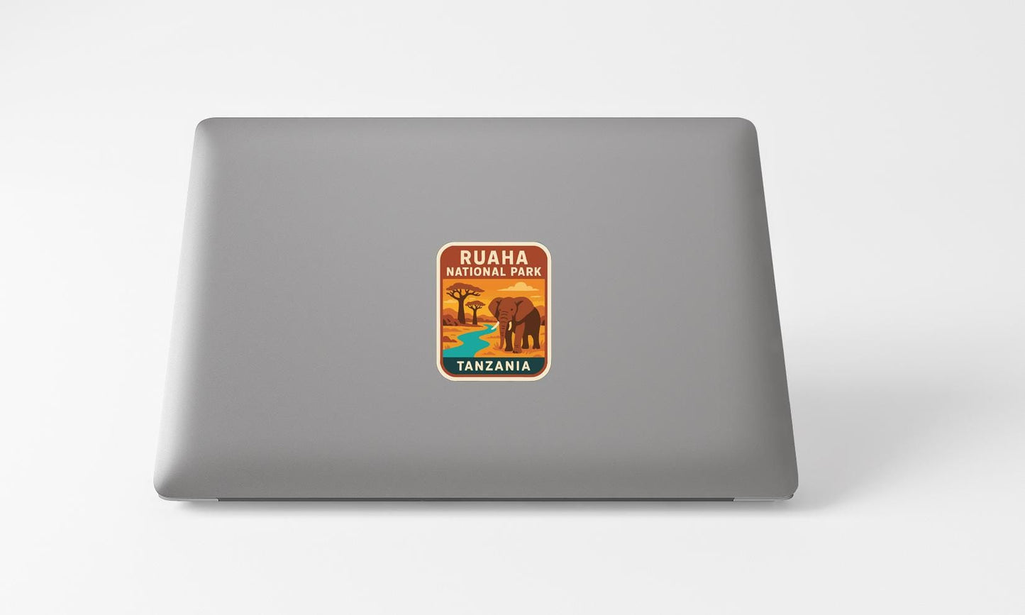 a sticker with an illustration of an elephant and the text "RUHA PARK TANZANIA" on a grey laptop.