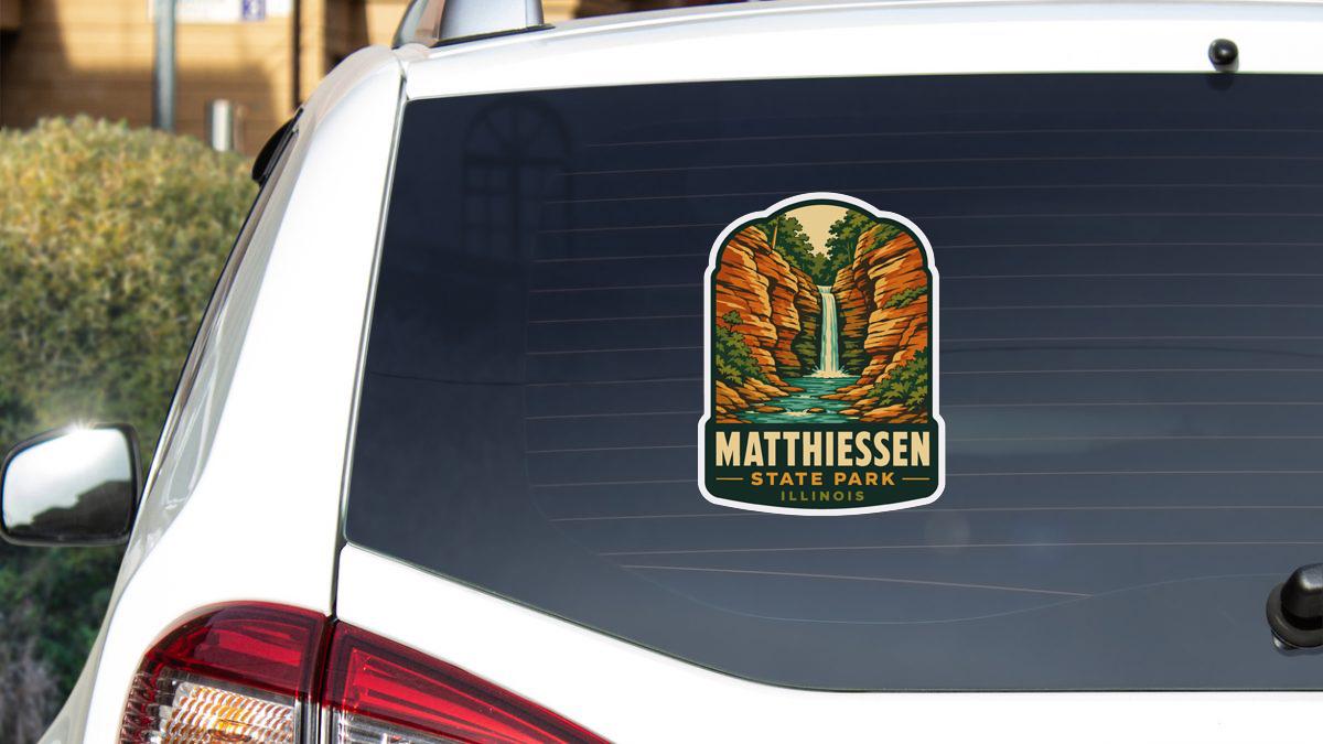 A sticker on the rear window of a white car, depicting a scenic landscape with a waterfall and mountains.