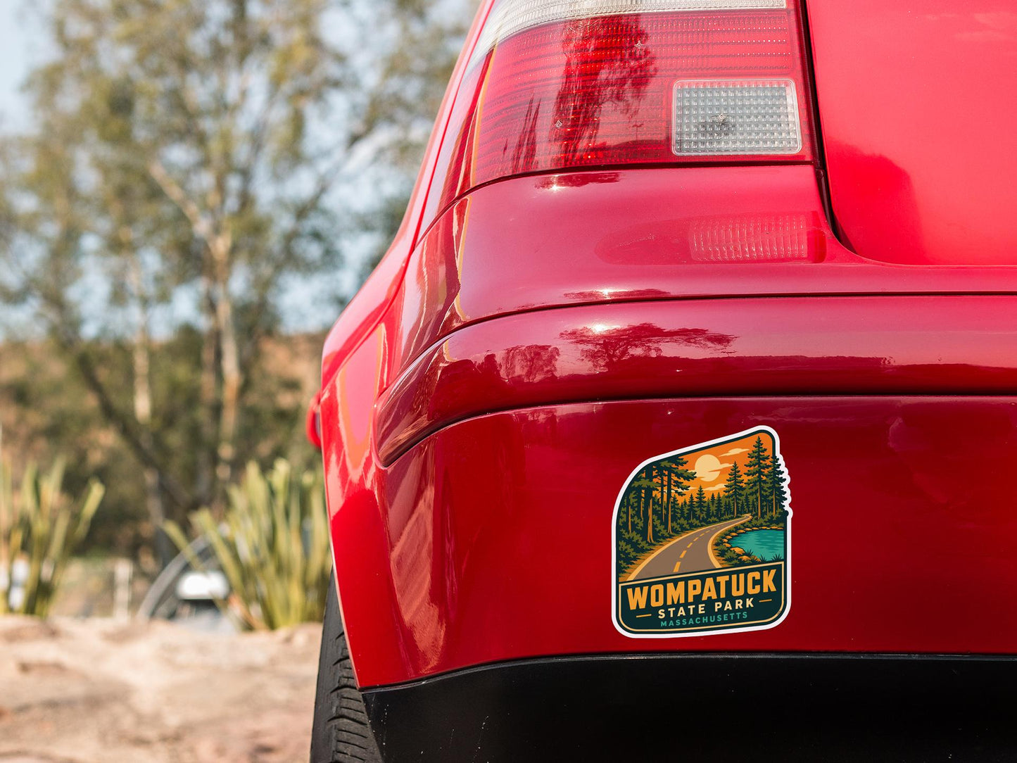 the rear end of a red car with a sticker on the bumper that says "Womptuck State Park Massachusetts".