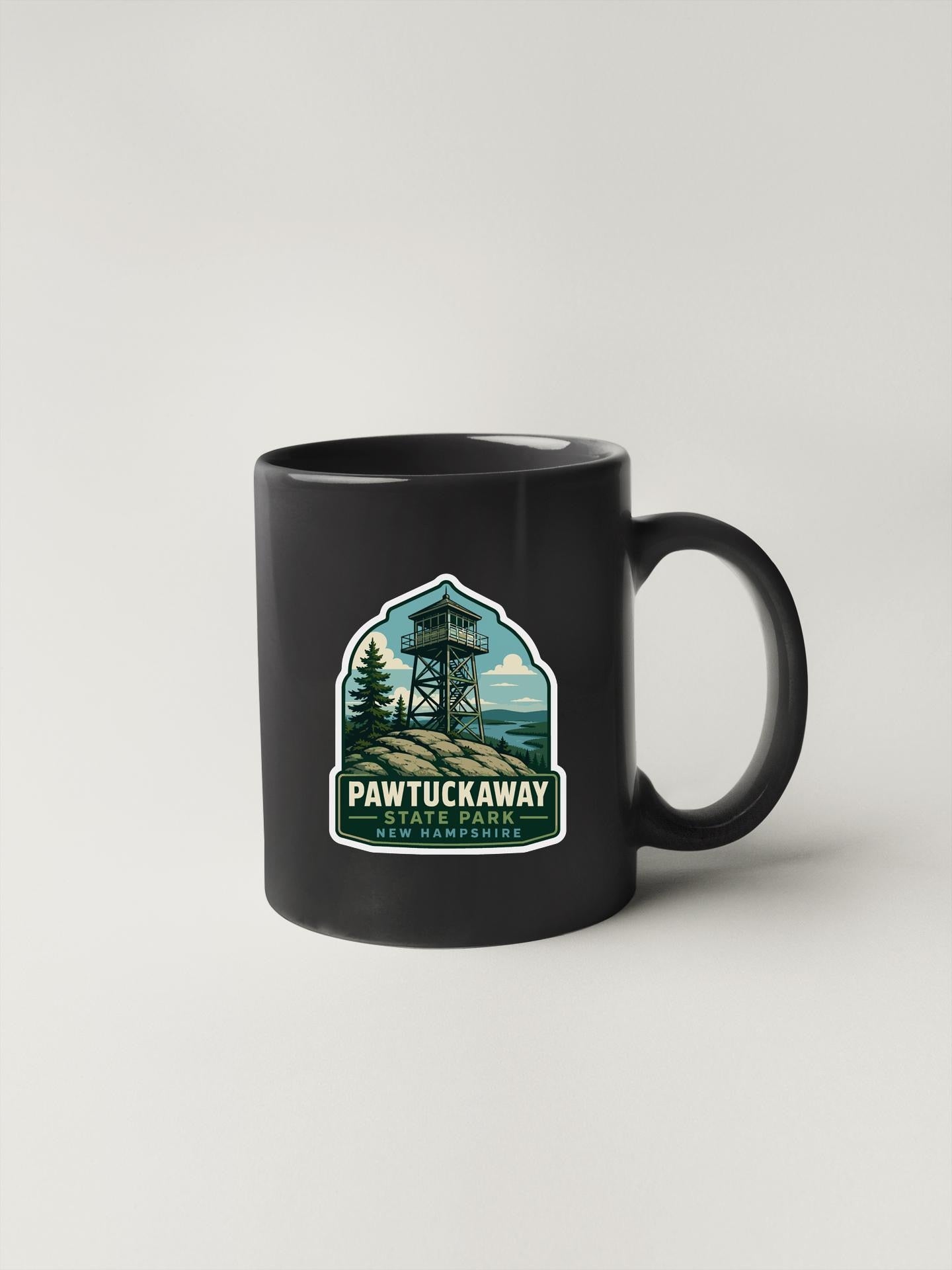 A black coffee mug with a label that says "Pawtuckaway" and "Pawtuckaway State Park" printed on it.
