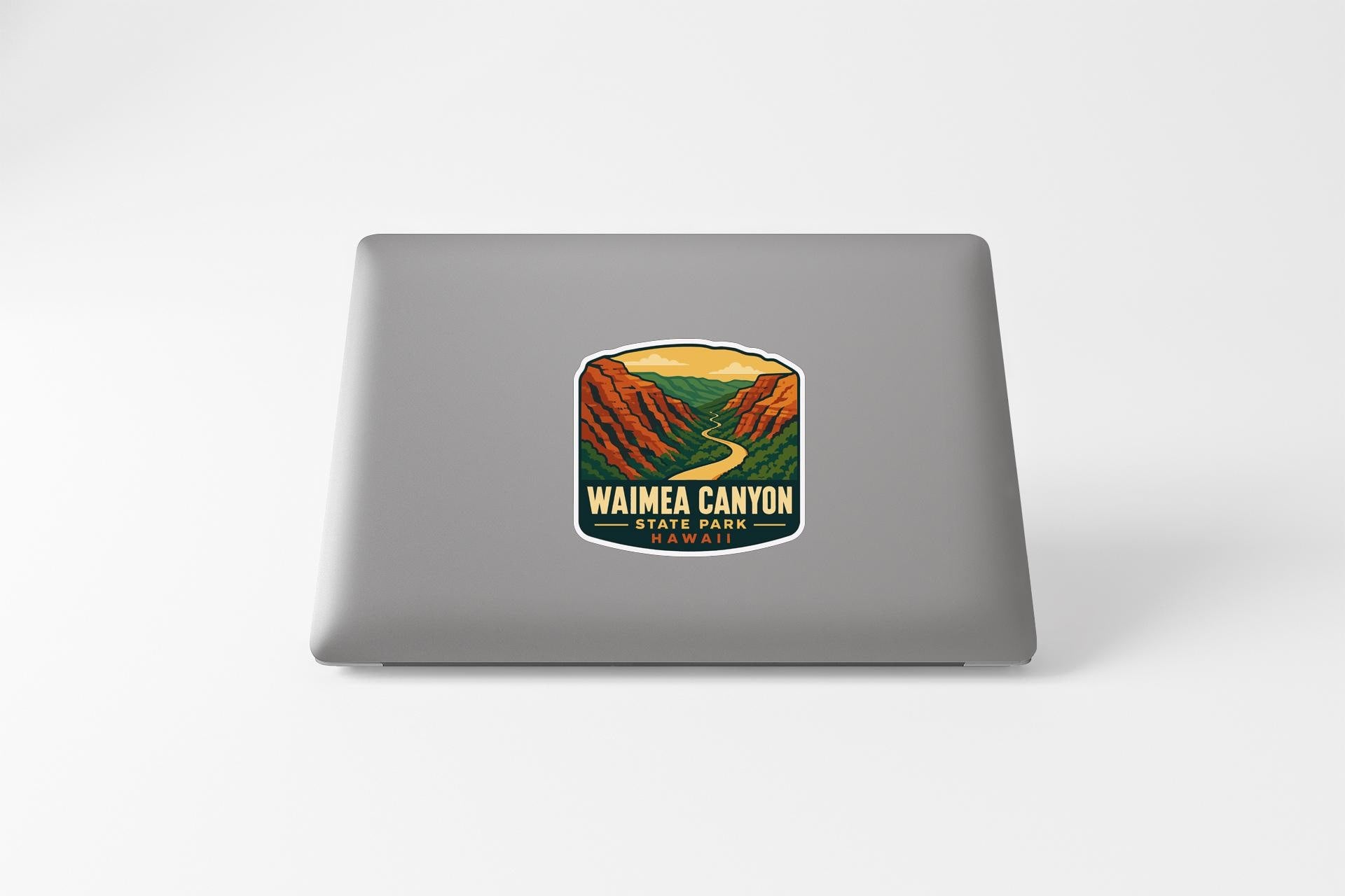 A sticker on the back of a laptop, depicting a scenic landscape with mountains and a winding road.
