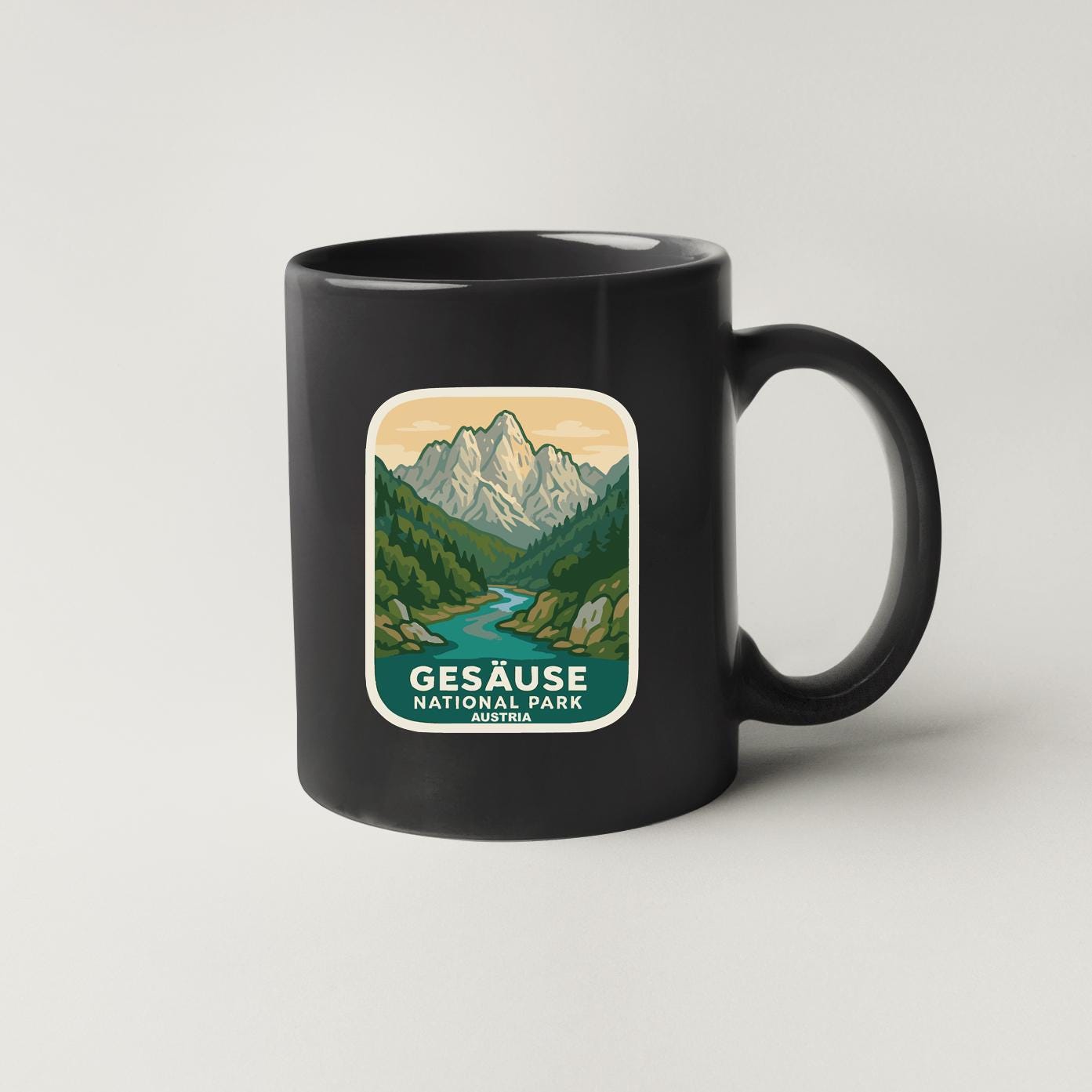 A black coffee mug with a graphic design depicting a mountain landscape and a river.