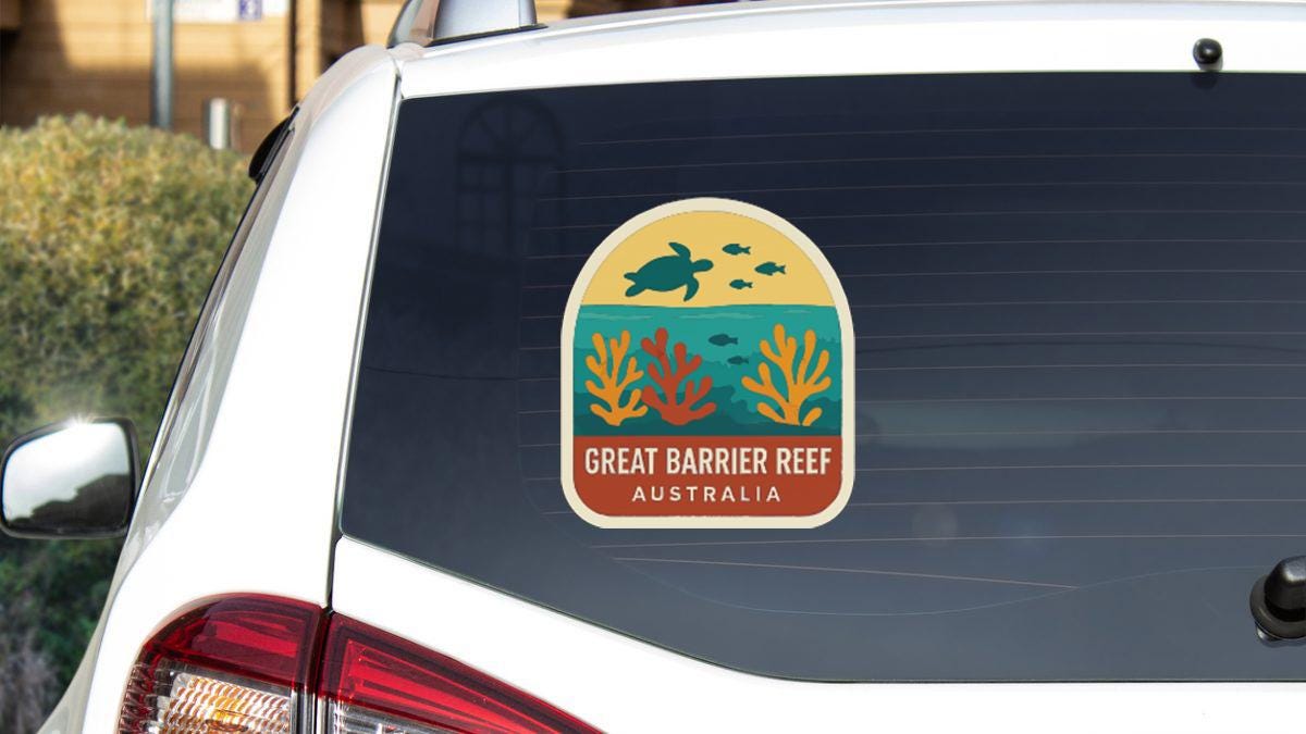 A sticker on the rear window of a white car, depicting a marine scene with a turtle and coral.