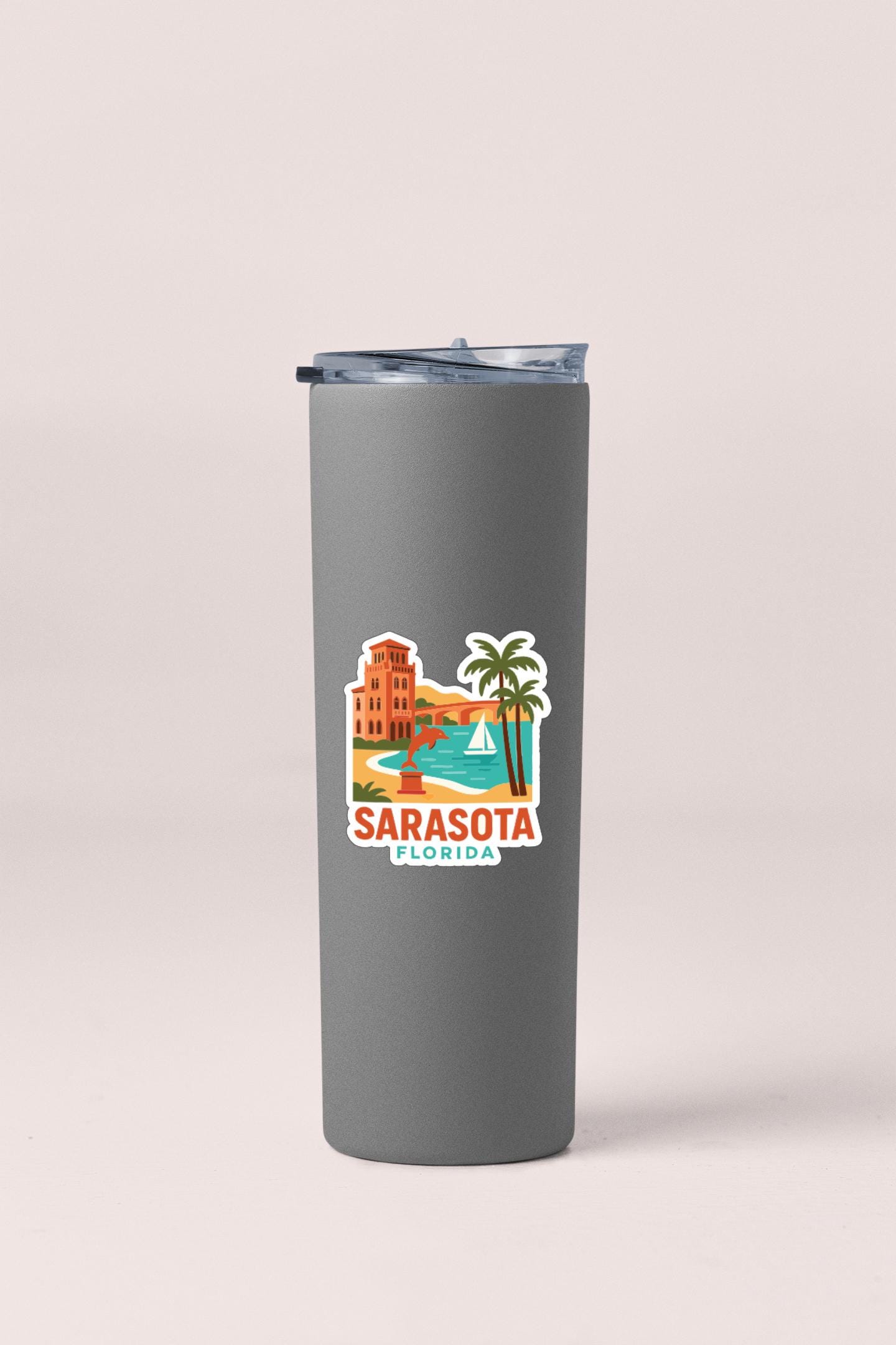 A gray insulated tumbler with a sticker depicting a tropical scene in Sarasota, Florida.