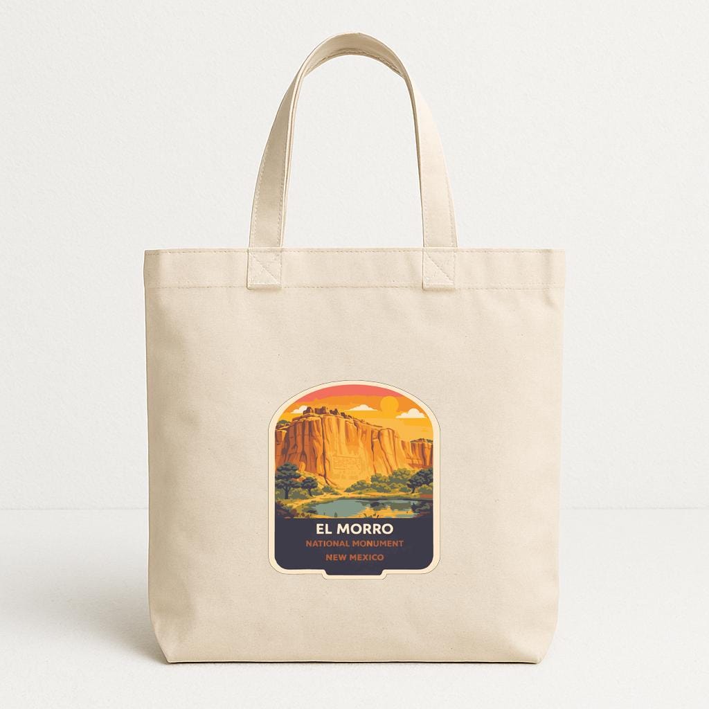 A beige tote bag with a printed label depicting a scenic landscape with mountains and a sunset.