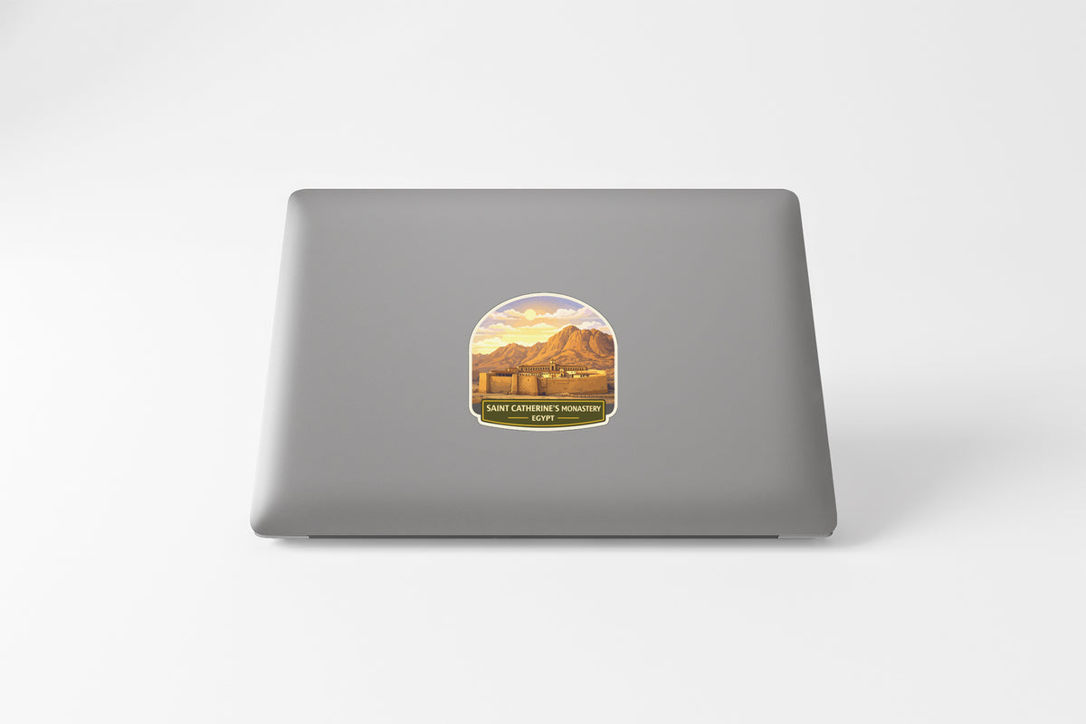 A sticker depicting a mountain landscape with a sunset in the background is placed on the back of a laptop computer.