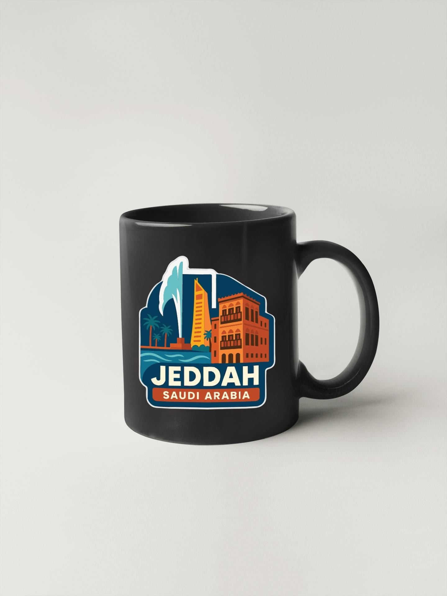 A black coffee mug with a graphic design featuring the city of Jeddah, Saudi Arabia, along with a palm tree and other landmarks.